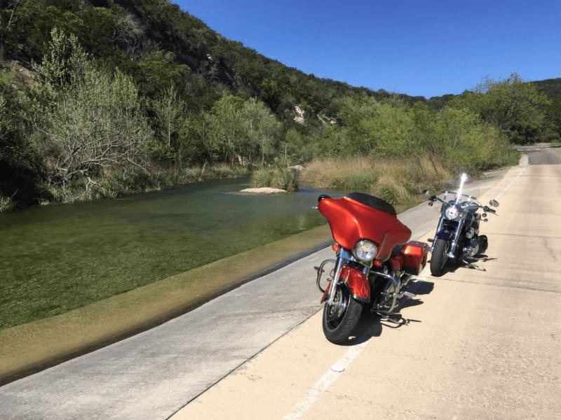 Motorcycles parked beside a clear creek at Lost Maples State Natural Area